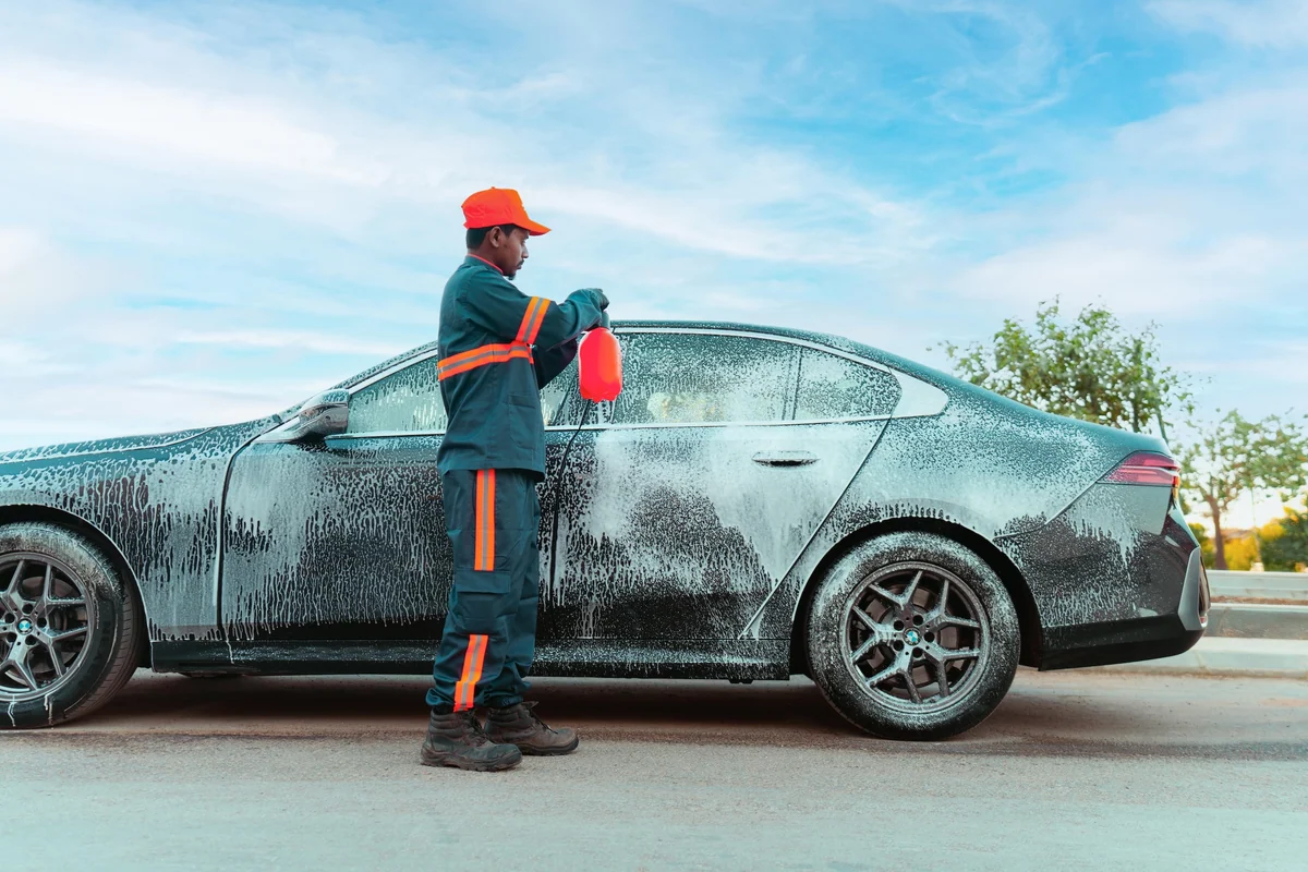 A Sweater technician washing a car with foam