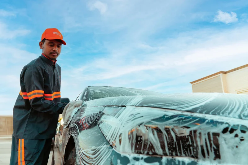 A Sweater technician cleaning a car exterior